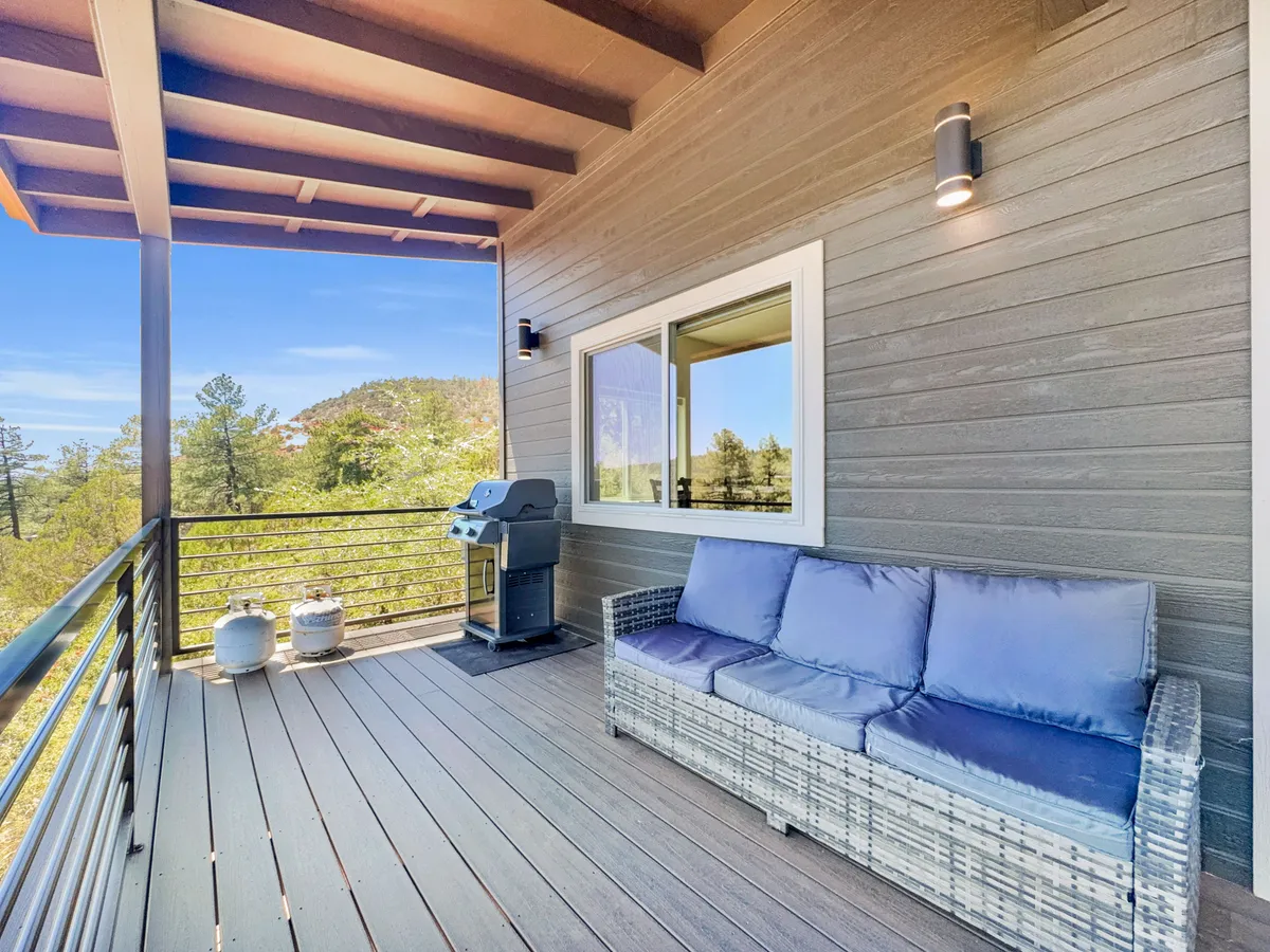 A spacious outdoor seating area is arranged around a grill, with a dining table that overlooks beautiful mountain views. The area is perfect for barbecuing, relaxing, or enjoying a meal as the sun sets, with plenty of space for a group to gather and celebrate together.