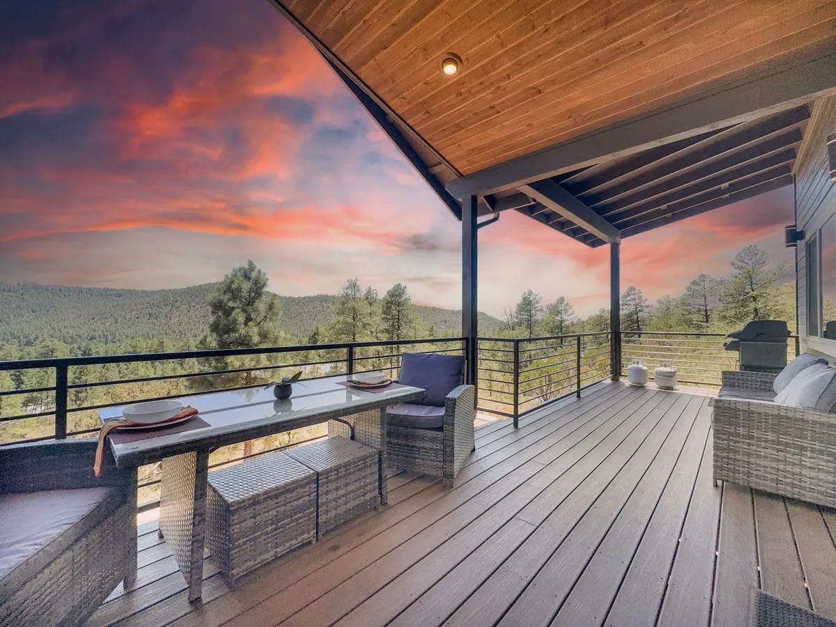 A spacious outdoor deck featuring a comfortable dining table, outdoor seating, a grill, and a stunning mountain view in the background. The setup invites guests to dine al fresco, host barbecues, or simply relax while taking in the scenery.