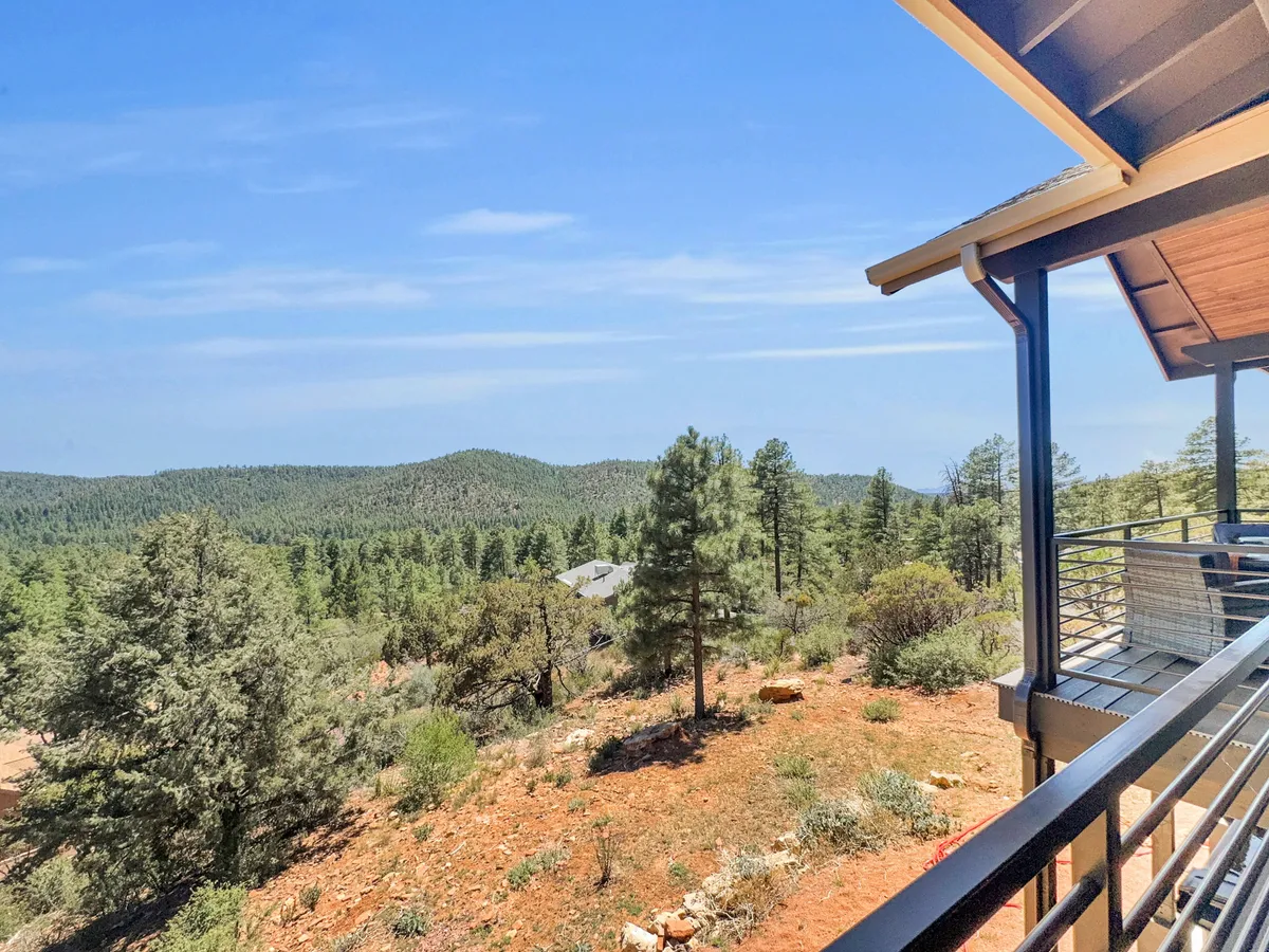 A sweeping view from the deck, featuring a mountain range, dense forest, and sturdy railing. The setting is ideal for wildlife spotting, sunrise coffee, or peaceful stargazing, with an open invitation to appreciate the beauty of Arizona’s high country.